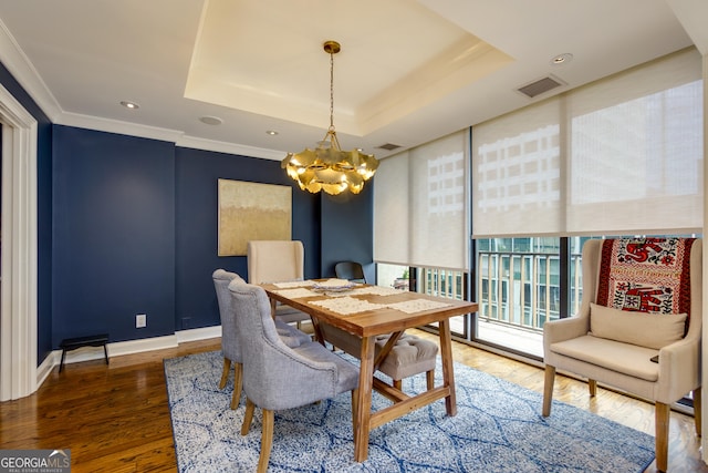 dining area featuring crown molding, baseboards, a chandelier, a tray ceiling, and wood finished floors