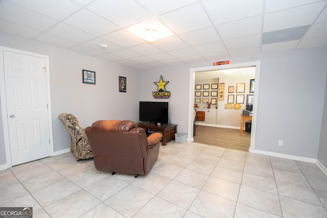 living room with light tile patterned flooring and a drop ceiling