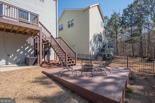 wooden deck with an outdoor fire pit, central air condition unit, fence, and stairs