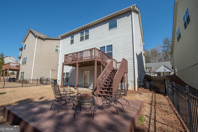 rear view of property featuring a deck, outdoor dining space, a fenced backyard, and stairway