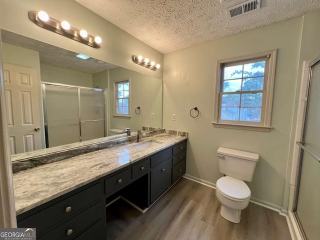 bathroom with hardwood / wood-style flooring, vanity, walk in shower, toilet, and a textured ceiling