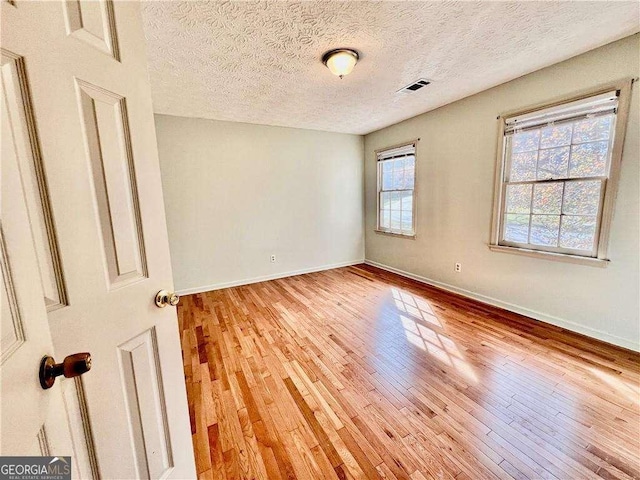 spare room featuring a textured ceiling and light wood-type flooring