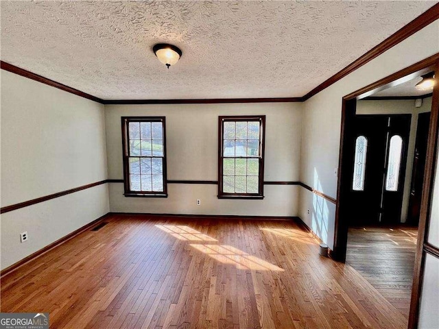 spare room featuring crown molding, a textured ceiling, and light hardwood / wood-style flooring