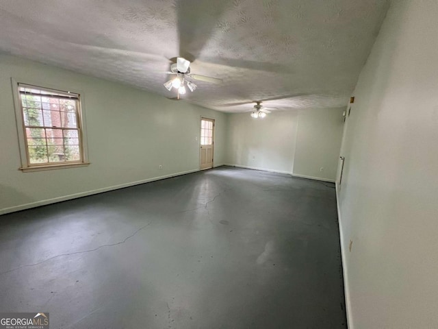 unfurnished room with ceiling fan and a textured ceiling