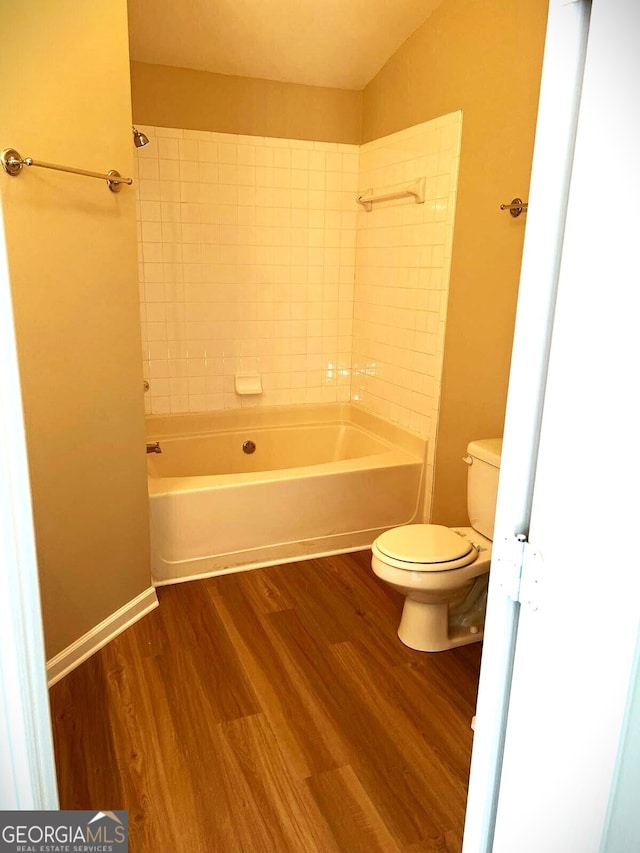 bathroom featuring toilet, tiled shower / bath combo, and hardwood / wood-style floors