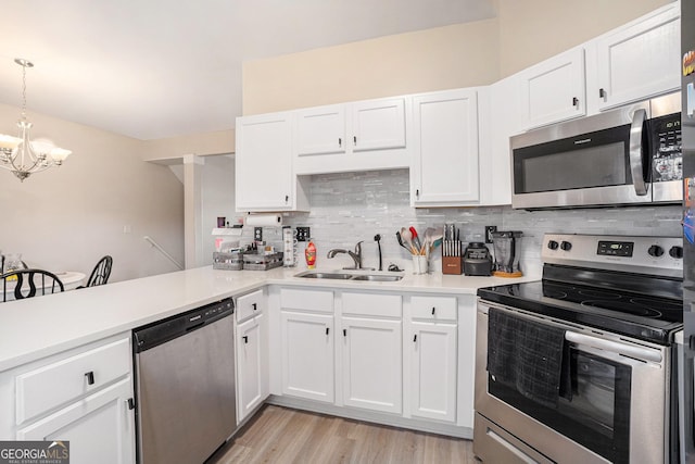 kitchen with pendant lighting, stainless steel appliances, sink, and white cabinets