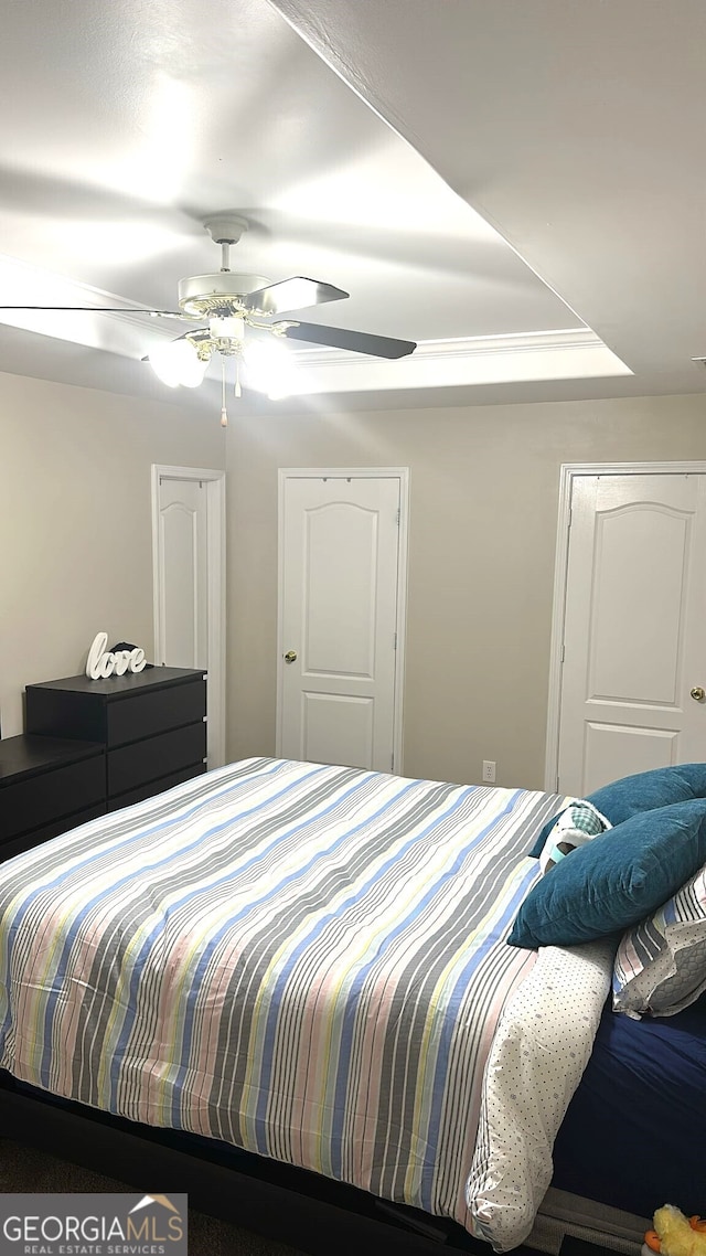 bedroom with ceiling fan and a raised ceiling