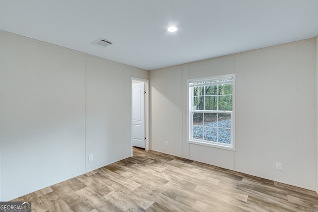 empty room with wood finished floors, visible vents, and recessed lighting