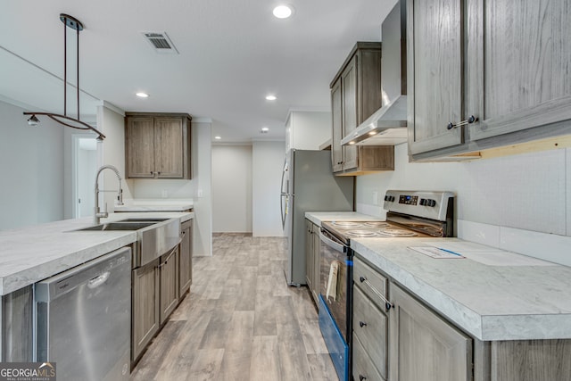 kitchen featuring a sink, visible vents, light wood-style floors, appliances with stainless steel finishes, and wall chimney range hood