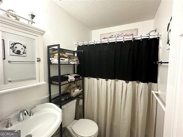 bathroom with walk in shower, sink, a textured ceiling, and toilet