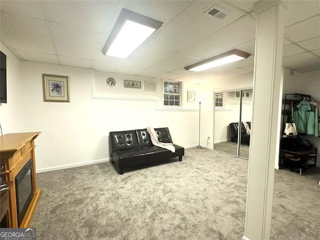 living area featuring carpet flooring and a paneled ceiling