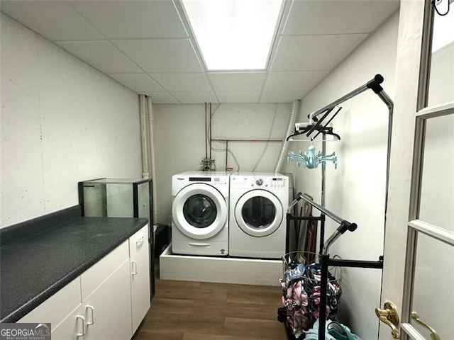 clothes washing area featuring cabinets, washer and dryer, and dark wood-type flooring