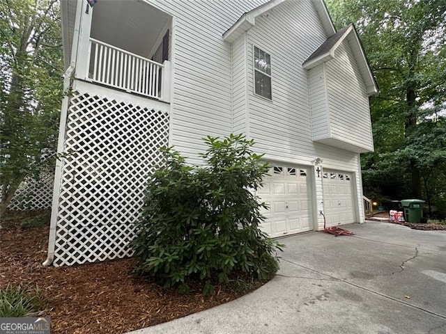 view of side of home with a garage and a balcony