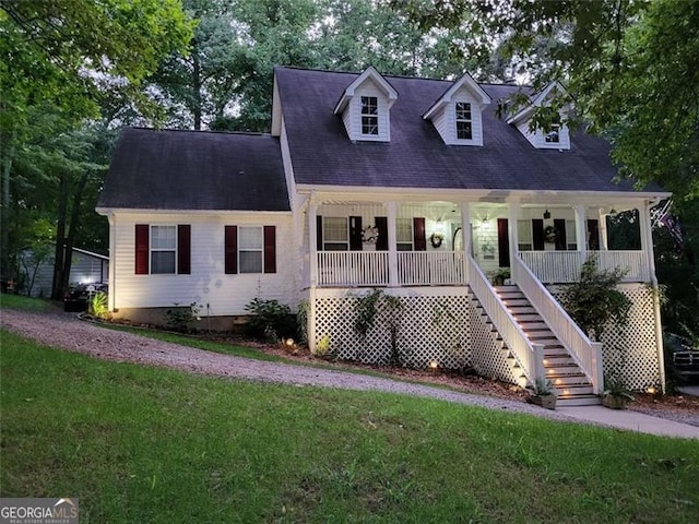 cape cod home featuring a front yard and covered porch