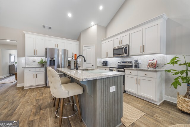 kitchen featuring light stone counters, white cabinetry, backsplash, and stainless steel fridge with ice dispenser