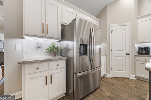 kitchen featuring stainless steel appliances, white cabinetry, vaulted ceiling, and light stone counters