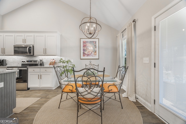 dining room featuring lofted ceiling, baseboards, an inviting chandelier, and wood finished floors