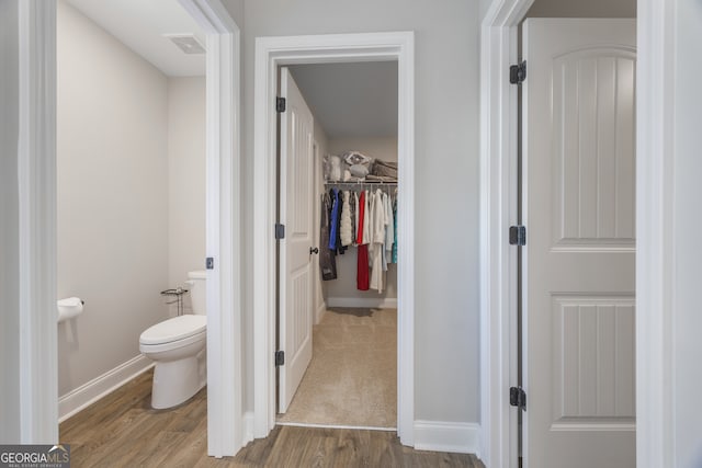 bathroom with visible vents, a spacious closet, toilet, wood finished floors, and baseboards