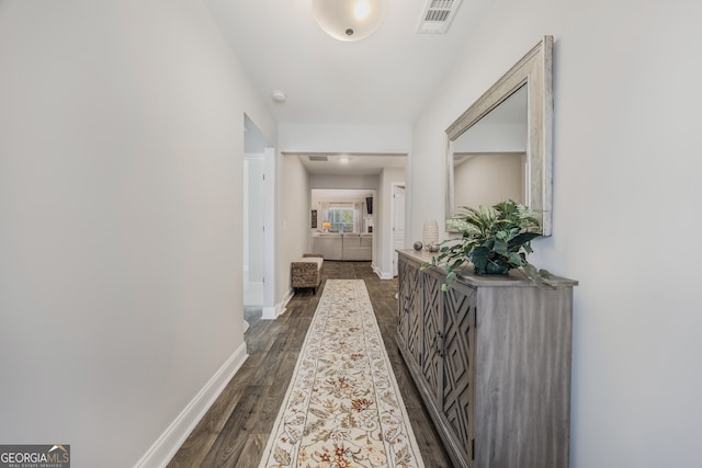 hall with dark wood-style floors, visible vents, and baseboards