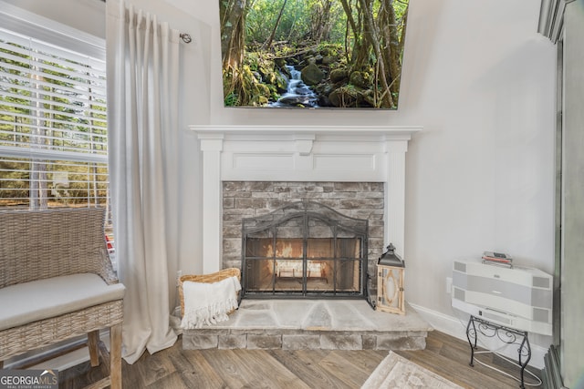 interior details featuring a wall mounted AC, a fireplace, wood finished floors, and baseboards