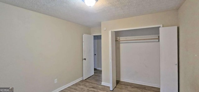 unfurnished bedroom with wood-type flooring, a textured ceiling, and a closet