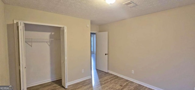 unfurnished bedroom with wood-type flooring, a textured ceiling, and a closet