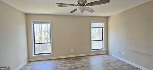 empty room featuring a healthy amount of sunlight, hardwood / wood-style floors, and a textured ceiling