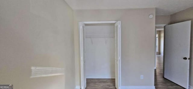 unfurnished bedroom featuring dark hardwood / wood-style flooring and a closet