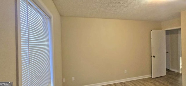 spare room featuring hardwood / wood-style flooring and a textured ceiling