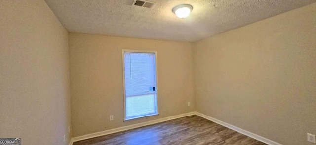 unfurnished room with dark wood-type flooring and a textured ceiling