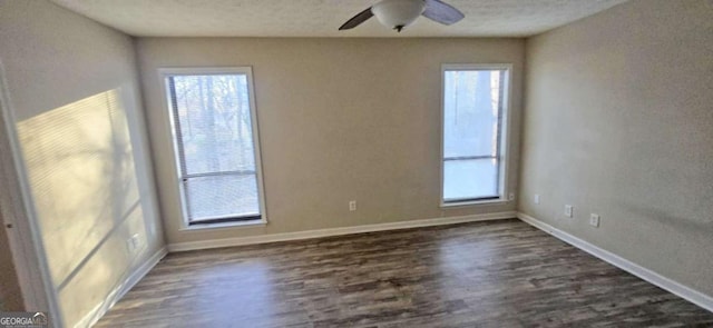 spare room with dark hardwood / wood-style floors, a wealth of natural light, and ceiling fan