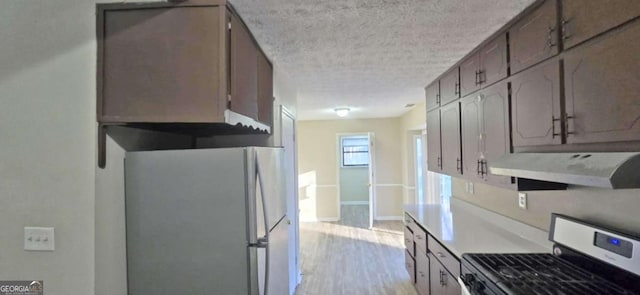 kitchen featuring stainless steel appliances, a textured ceiling, and light hardwood / wood-style flooring