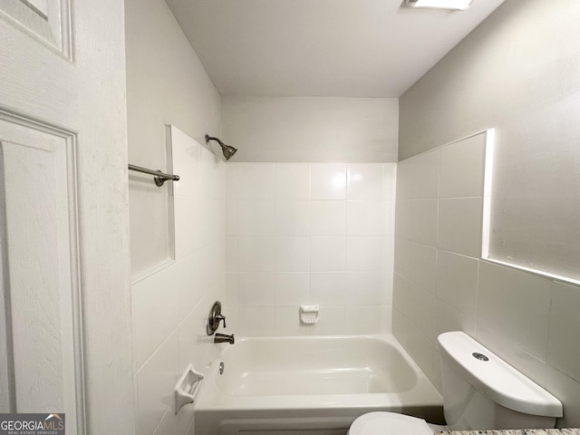 bathroom with tiled shower / bath combo and toilet