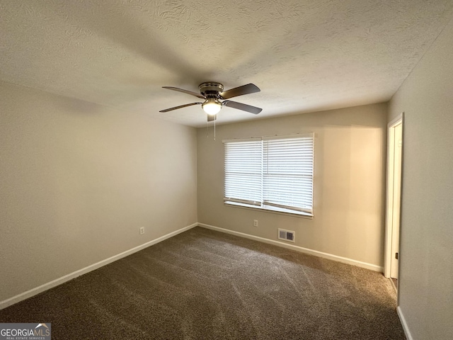 empty room with ceiling fan, dark carpet, and a textured ceiling