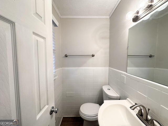 bathroom with sink, tile walls, ornamental molding, a textured ceiling, and toilet