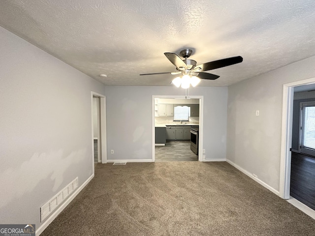 spare room with a textured ceiling, ceiling fan, and carpet