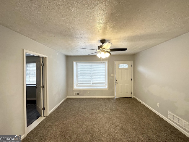 carpeted spare room featuring ceiling fan, a textured ceiling, and a wealth of natural light