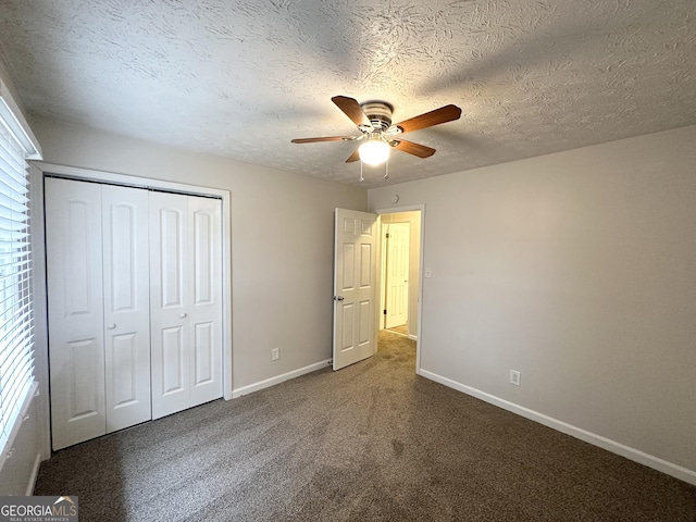 unfurnished bedroom featuring ceiling fan, a textured ceiling, dark carpet, and a closet