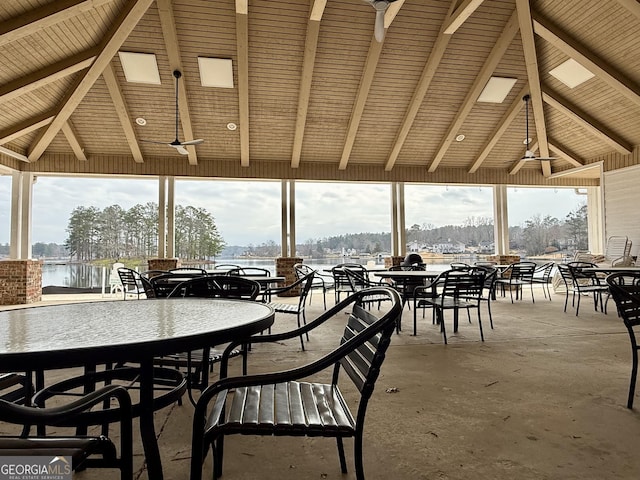 sunroom with vaulted ceiling with beams, a healthy amount of sunlight, and a water view