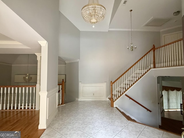 entryway with a notable chandelier, ornamental molding, and a high ceiling