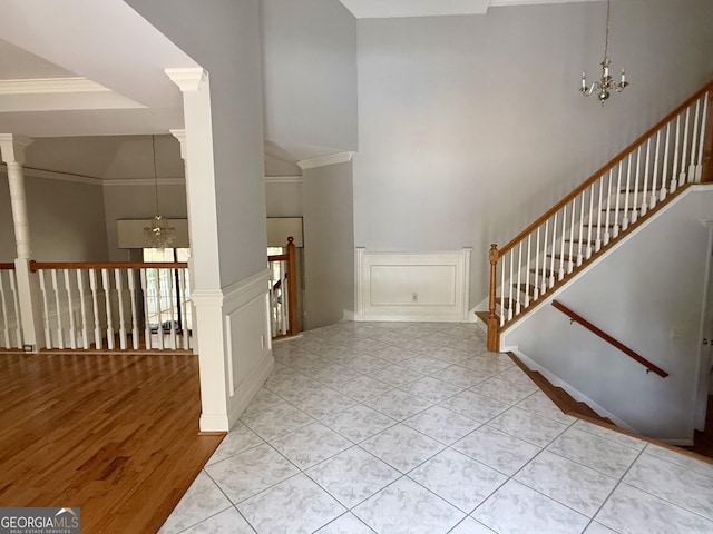 tiled foyer with a high ceiling, crown molding, and a notable chandelier