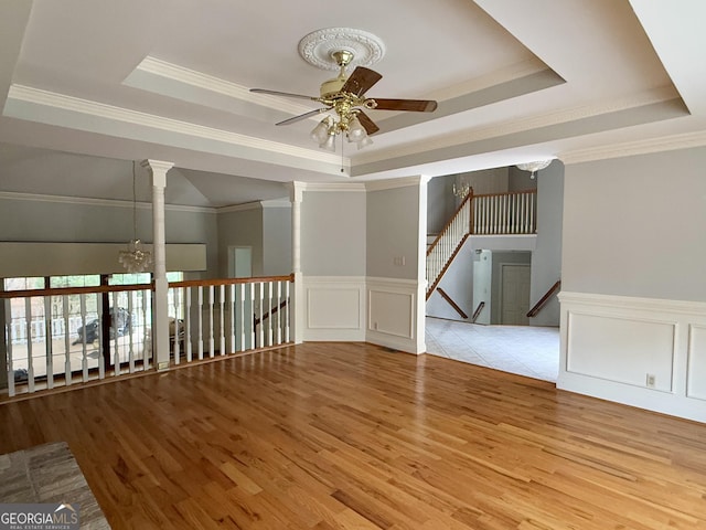 unfurnished room with crown molding, ceiling fan with notable chandelier, light hardwood / wood-style flooring, and a raised ceiling