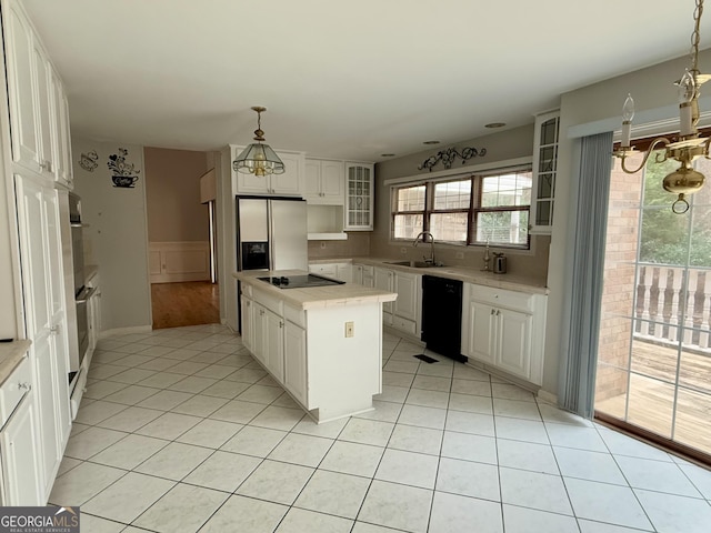 kitchen with sink, black appliances, hanging light fixtures, and white cabinets