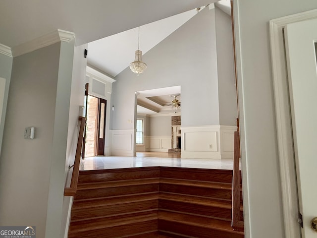 staircase featuring crown molding, ceiling fan, and vaulted ceiling