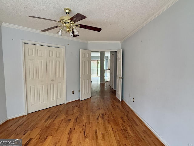 unfurnished bedroom featuring crown molding, a closet, hardwood / wood-style floors, and a textured ceiling