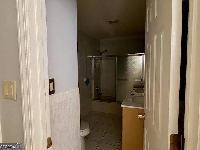 full bathroom featuring vanity, bath / shower combo with glass door, tile patterned floors, and toilet