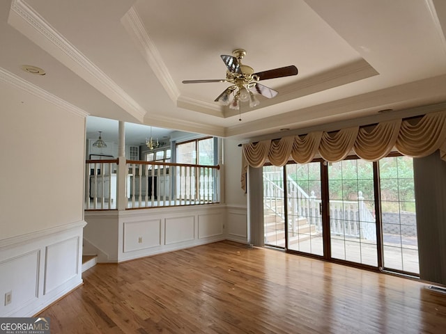 unfurnished room with crown molding, ceiling fan with notable chandelier, light hardwood / wood-style floors, and a tray ceiling