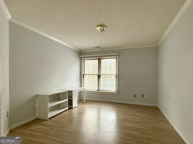 empty room with crown molding, light hardwood / wood-style flooring, and a textured ceiling