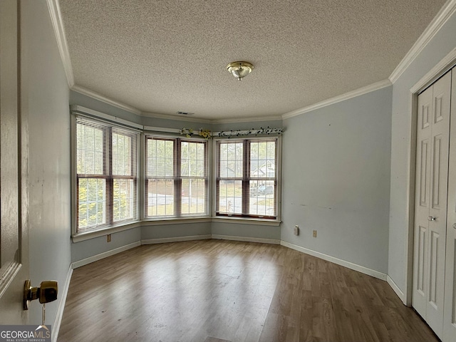 unfurnished room featuring hardwood / wood-style flooring, ornamental molding, and a textured ceiling