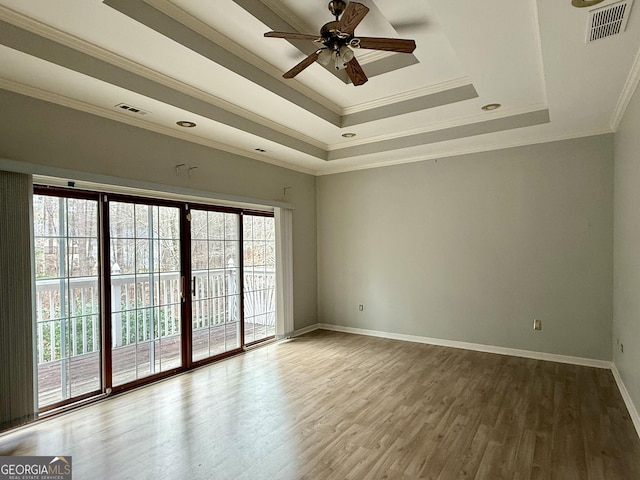 empty room with hardwood / wood-style flooring, ornamental molding, a raised ceiling, and ceiling fan